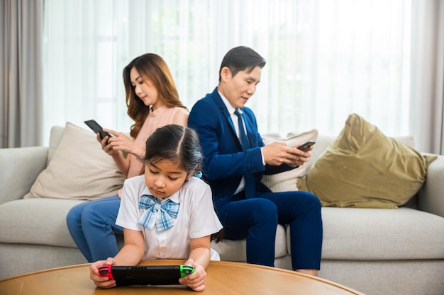La familia no se preocupa por los demás. Los padres asiáticos ignoran a sus hijos y miran su teléfono móvil en casa, la dependencia de los aparatos usa en exceso la adicción a las redes sociales de Internet en el sofá de la sala de estar