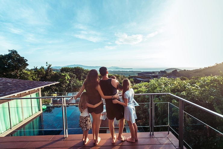 Família no terraço à beira-mar, observando o pôr do sol. Vista traseira. Phuket. Tailândia