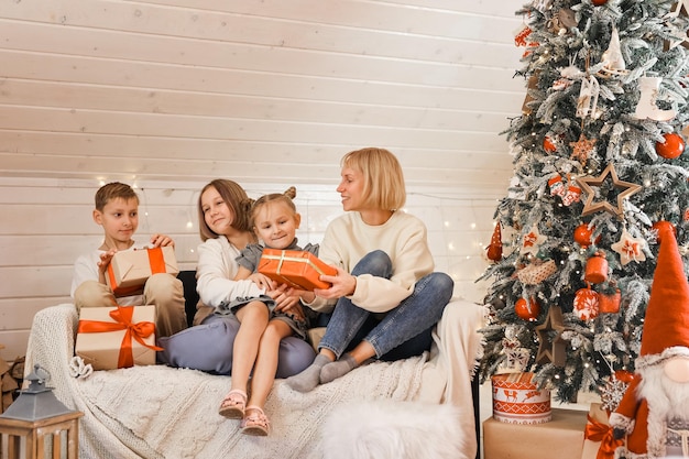 Familia en Nochebuena. Niños abriendo regalos. Niños bajo el árbol de Navidad con cajas de regalo. Habitación decorada de año nuevo. Acogedora y cálida noche de invierno en casa.