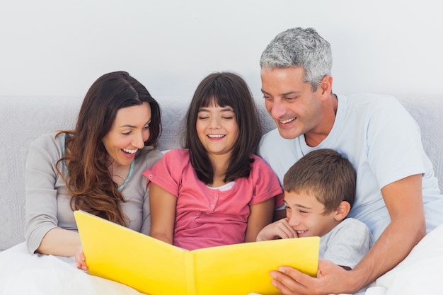 Família olhando juntos para o álbum de fotos na cama