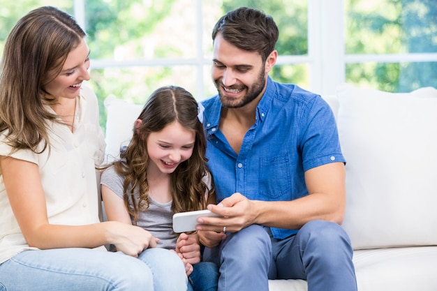 Foto família olhando para o telefone inteligente enquanto está sentado no sofá