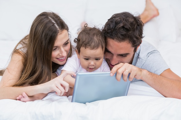 Família olhando tablet digital na cama