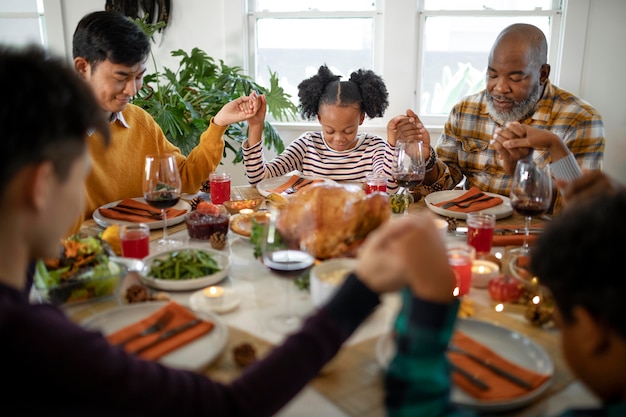 Família orando junta antes do jantar do dia de ação de graças