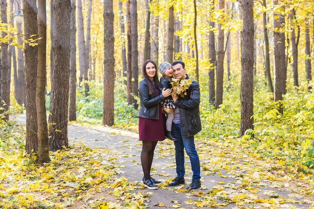 Familia, otoño, concepto de personas - familia joven de raza mixta caminando en el parque en día de otoño