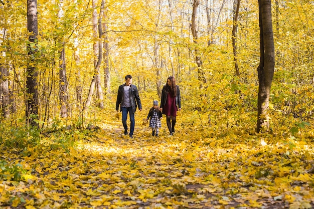 Família, outono, conceito de pessoas - jovem família caminhando no parque no dia de outono