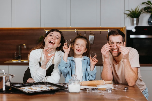 Foto familia de padre y madre con hija cocinando en la cocina