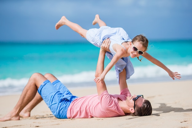Familia de padre y niña deportiva divirtiéndose en la playa