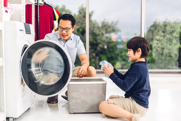Família pai asiático e filho menino se divertindo fazendo tarefas domésticas, lavando roupas sujas na máquina de lavar roupa juntos na lavanderia em casa