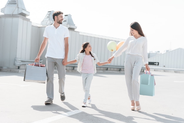 Família, pai, mãe e filha com sacolas de compras.