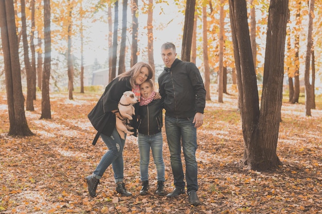 La familia pasa tiempo en el parque de otoño con un perro. Padre, madre e hija y perro jack russell terrier divirtiéndose en otoño