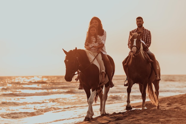 La familia pasa tiempo con sus hijos mientras montan a caballo juntos en una playa de arena. Enfoque selectivo. foto de alta calidad