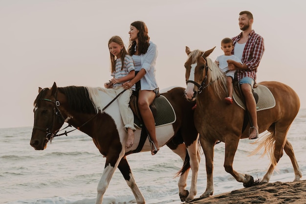 La familia pasa tiempo con sus hijos mientras montan a caballo juntos en una playa de arena. Enfoque selectivo. foto de alta calidad