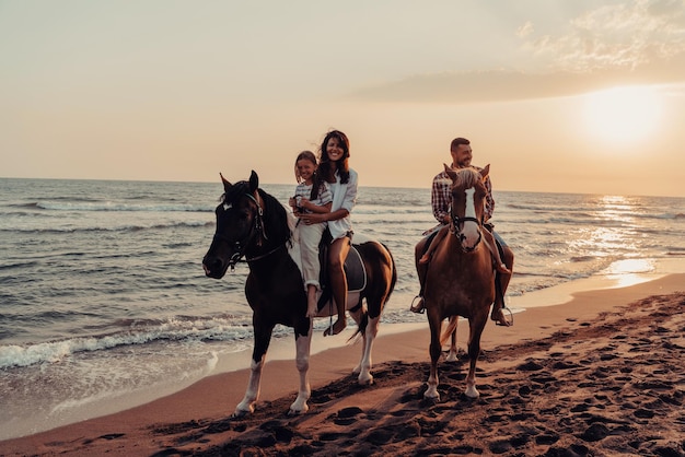 La familia pasa tiempo con sus hijos mientras montan a caballo juntos en una playa de arena. Enfoque selectivo. foto de alta calidad