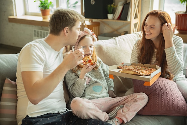 Foto familia pasando un buen rato juntos en casa, se ve feliz y alegre, comiendo pizza