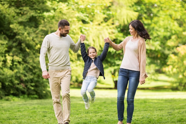 familia, paternidad, adopción y concepto de personas - madre feliz, padre y niña caminando en el parque de verano y divirtiéndose