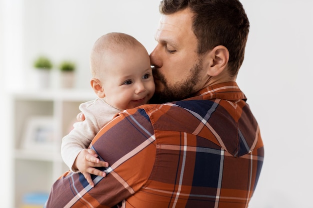 Foto la familia la paternidad y la gente concepto padre feliz besando al niño bebé en casa