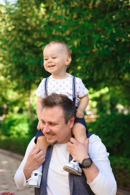 Familia, paternidad - padre y niño caminando en el parque de verano.