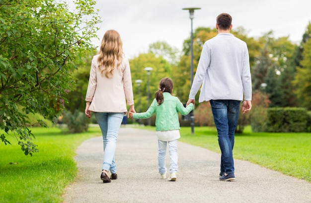 Foto família, paternidade, adoção e conceito de pessoas - feliz mãe, pai e garotinha andando no parque de verão