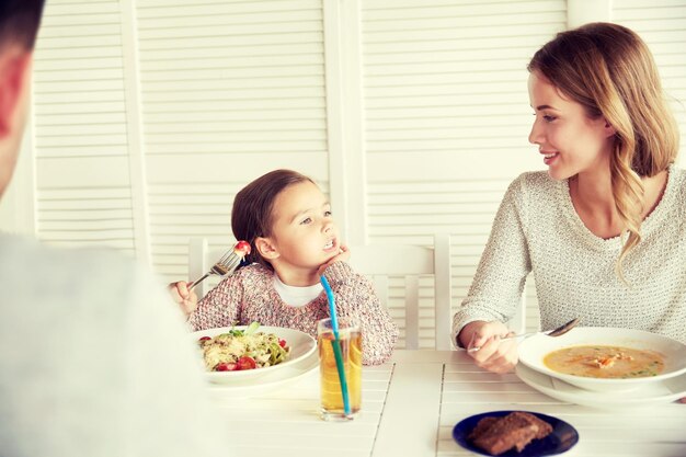 família, paternidade, comunicação e conceito de pessoas - feliz mãe, pai e filha jantando e conversando no restaurante ou café