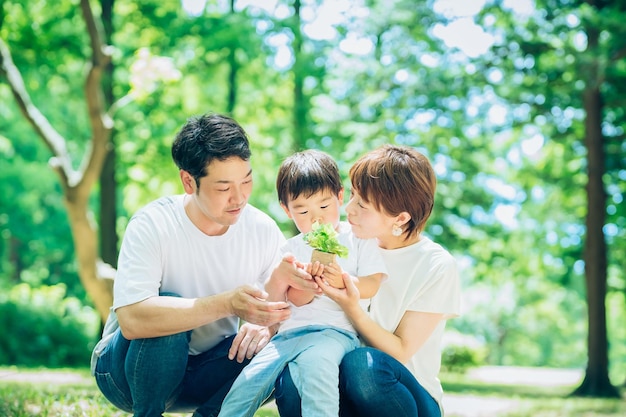 Una familia con una pequeña planta en maceta en el bosque.