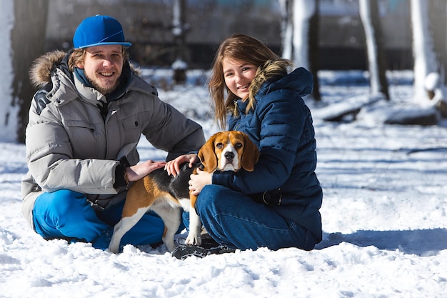 Familia con perro beagle durante un paseo por el bosque de invierno