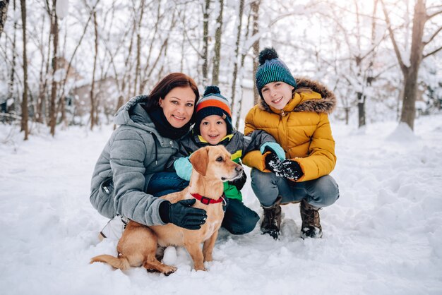 Familia con perro jugando en la nieve.