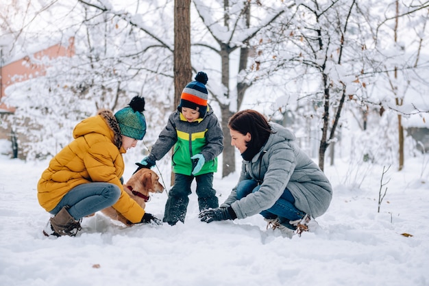 Familia con perro jugando en la nieve.