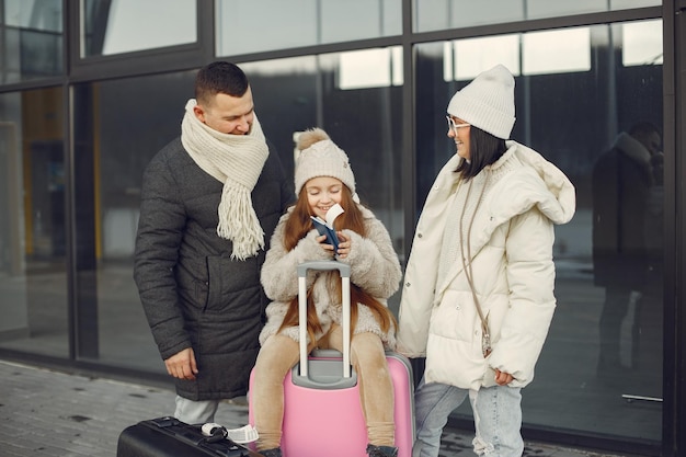 Familia de pie al aire libre con equipaje y comprobando pasaportes