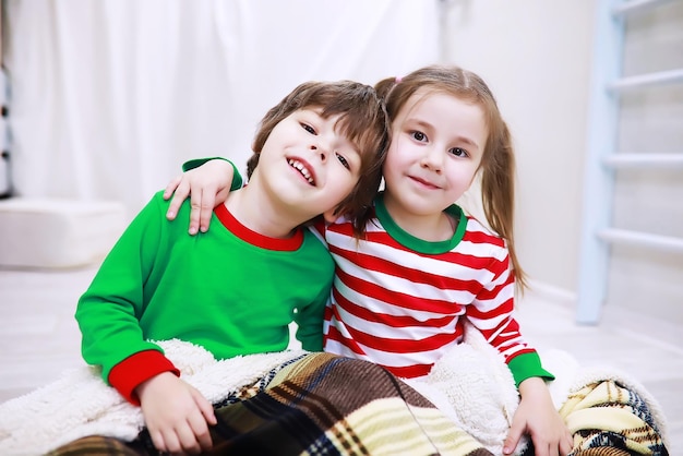 Una familia en pijama de rayas descansa en casa. Niños disfrazados de duendes yacen en el sofá. Una familia feliz.