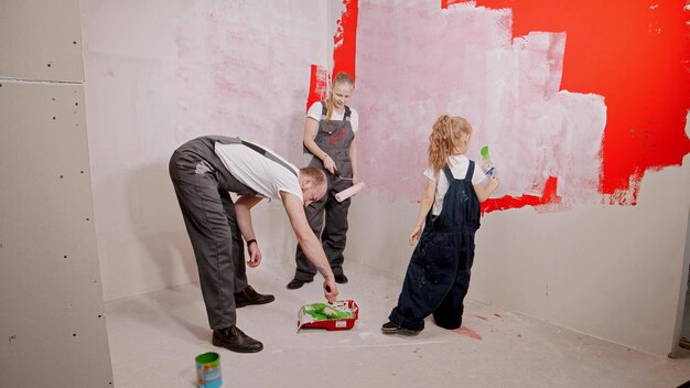 Família pintando paredes no novo apartamento aplicando a tinta nos rolos