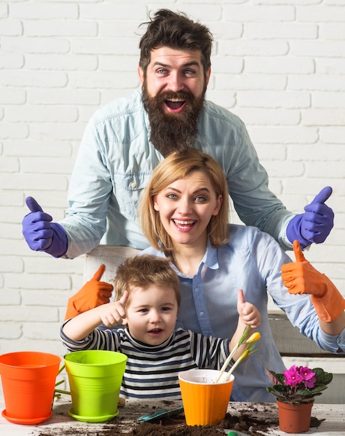 Foto familia plantando flores juntas. el hijo ayuda a los padres a cuidar las plantas.