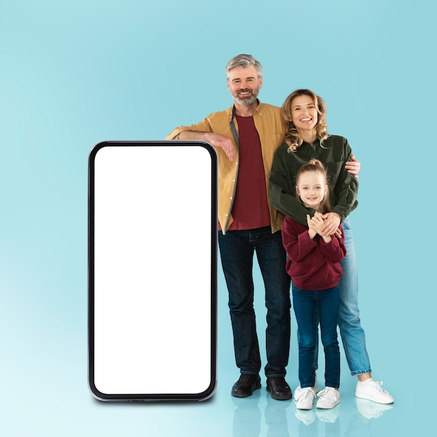 Família posando com celular enorme com fundo azul de tela vazia