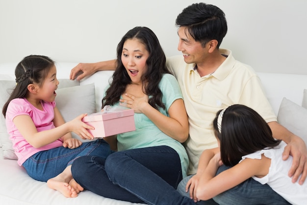 Familia presenta madre sorprendida con una caja de regalo en la sala de estar