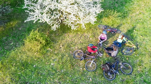 Familia de primavera ciclismo en bicicleta vista aérea de drones desde arriba felices padres activos con niños