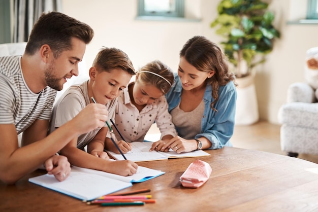 La familia que aprende junta crece junta Captura de una feliz familia joven de cuatro integrantes que hacen la tarea juntos