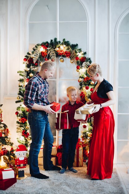Família que desembrulha o presente de Natal contra a decoração festiva bonita.