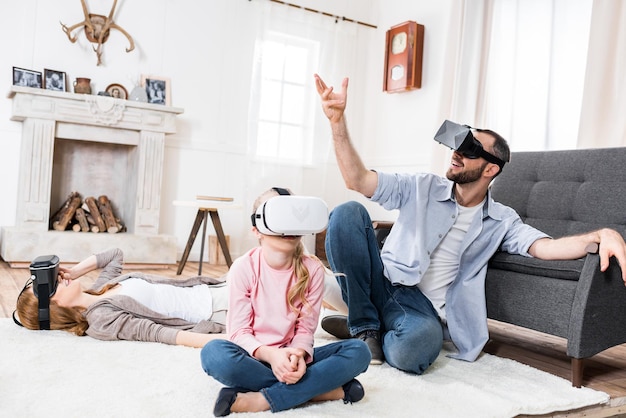 Familia que usa auriculares de realidad virtual mientras está sentado y gesticulando