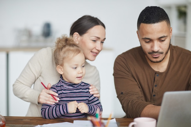 Familia de raza mixta usando una computadora portátil en casa