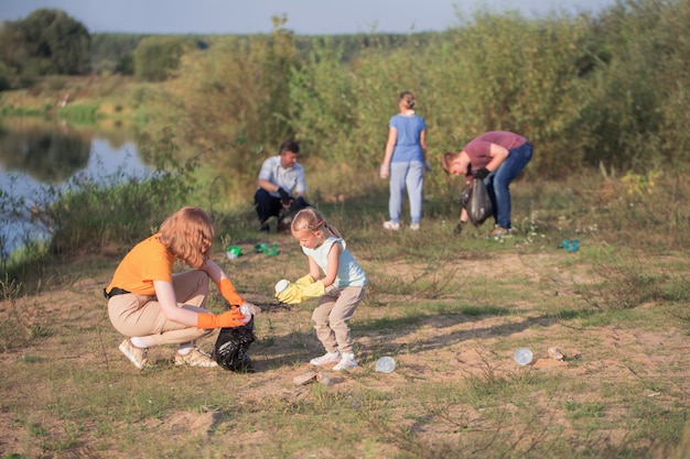 Familia recoge basura en la playa en verano