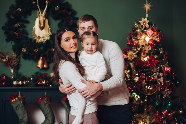 Foto familia en regalos junto al árbol de navidad.