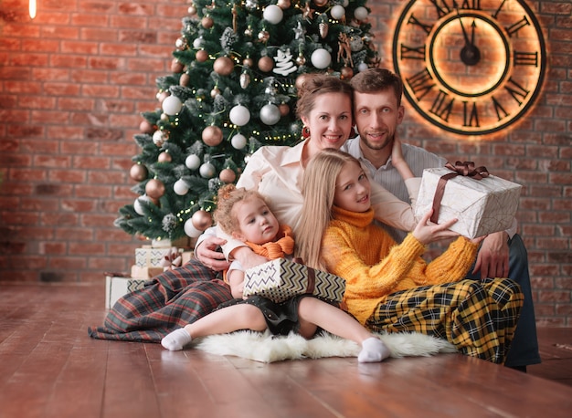 Familia con regalos de Navidad en una acogedora sala de estar.