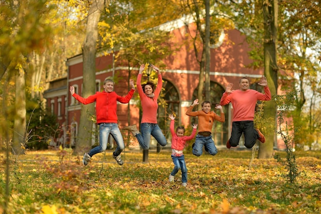 Familia relajándose en el parque de otoño saltando