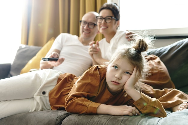 Familia relajante en casa. A la niña aburrida no le gustan los programas de televisión para adultos.