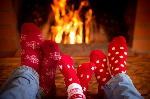 Família relaxando em casa. Pés em meias de Natal perto da lareira. Conceito de férias de inverno