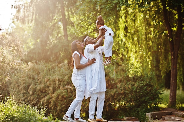 Familia rica afroamericana divirtiéndose en puesta de sol. Padre arroja a su hija en sus manos