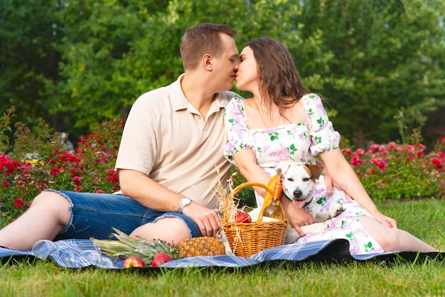 Familia romántica joven pareja en el jardín en un picnic besando a la mujer enamorada y al hombre en la hierba con ...