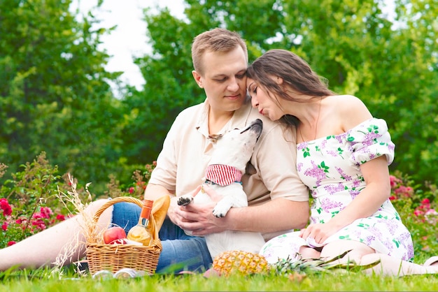 Familia romántica joven pareja en el jardín en un picnic mujer enamorada y hombre en la hierba con su ...