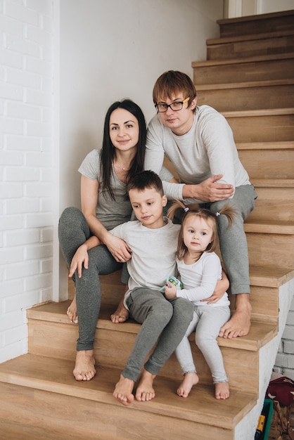 Foto familia en ropa de casa gris. en la casa sobre escalones de madera. gran h