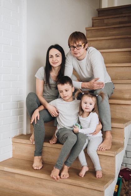 Familia en ropa de casa gris. En la casa sobre escalones de madera. Gran h