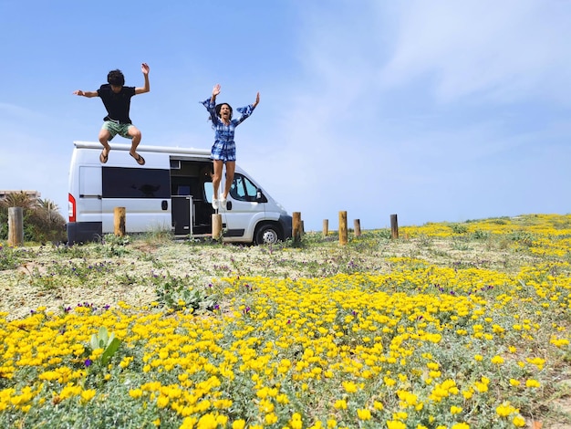 Familia saltando de alegría en un campo de flores y una autocaravana